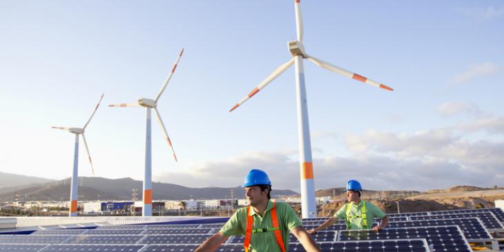 Clean energy workers, solar panels and wind turbines