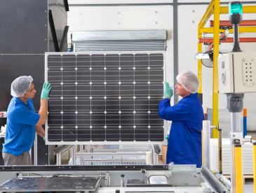 Two people carrying a solar panel